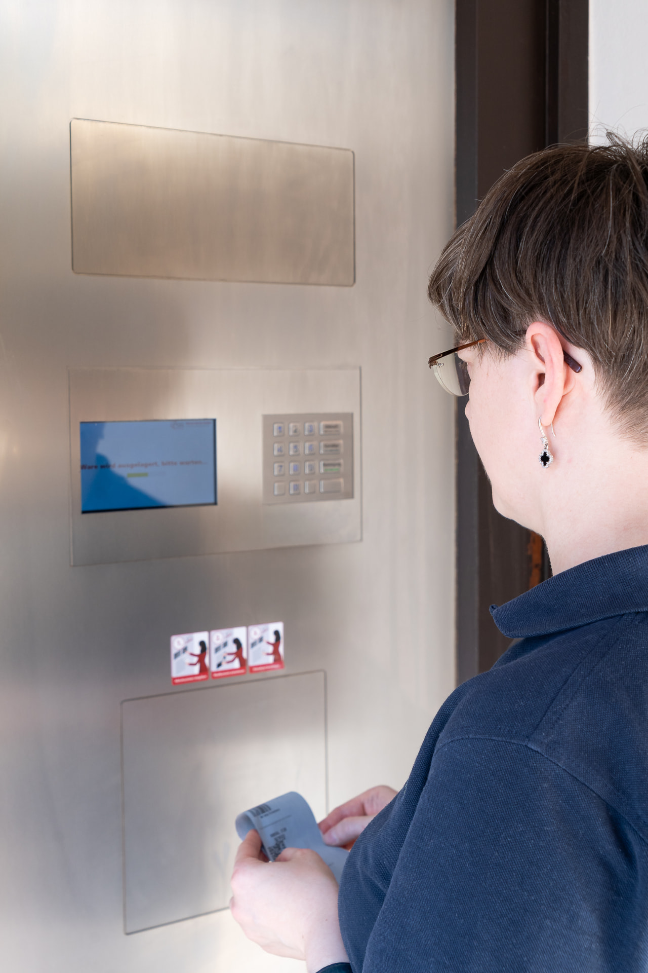 Kundin am Abholautomaten der Kreuz-Apotheke